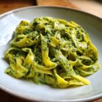 Nahaufnahme von leuchtend gelben Tagliatelle, bedeckt mit einer cremigen, grünen Bärlauch Tagliatelle Soße.