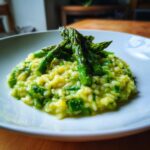 Nahaufnahme eines cremigen Spargelrisotto, garniert mit knackigen grünen Spargelspitzen.