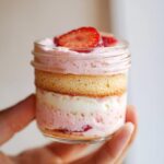 Nahaufnahme eines geschichteten Erdbeertiramisu im Glas, garniert mit frischen Erdbeerscheiben.