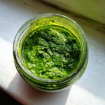 Nahaufnahme von leuchtend grüner, selbstgemachter Bärlauchpaste in einem kleinen Glas.