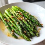 Nahaufnahme von perfekt gebratenem grünen Spargel, beträufelt mit Knoblauchbutter.