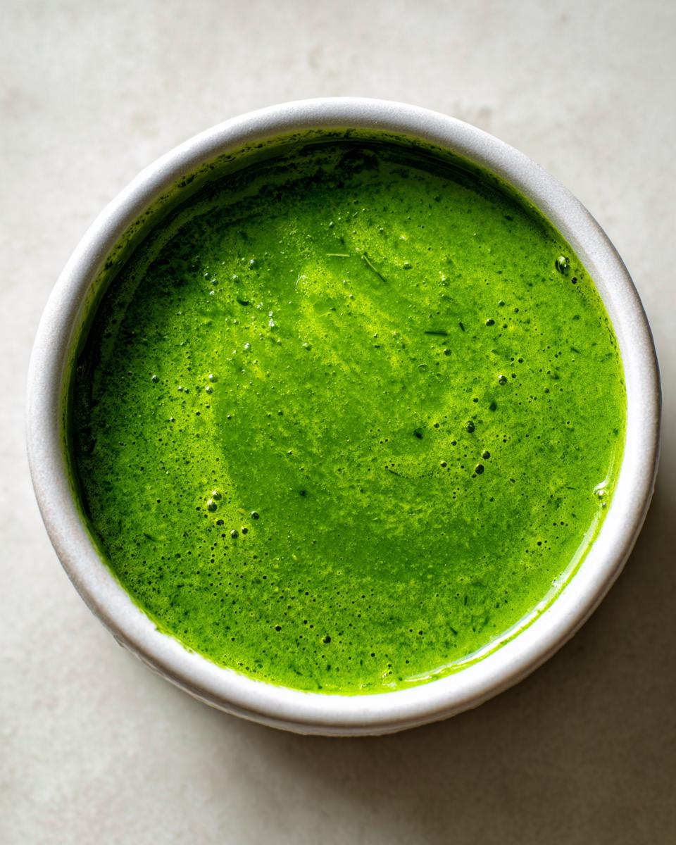 Nahaufnahme einer leuchtend grünen Bärlauchsuppe in einer weißen Schale, die die intensive Farbe zeigt.