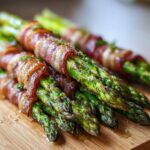Nahaufnahme von saftigem grünem Spargel im Schinkenmantel, leicht gebräunt und glänzend.