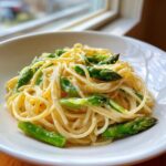Nahaufnahme von cremiger Zitronenpasta mit leuchtend grünem Spargel in einer weißen Schüssel.