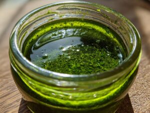 Nahaufnahme eines kleinen Glases mit leuchtend grünem Bärlauch-Pesto, bedeckt mit einer Schicht Öl.