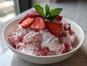 Nahaufnahme von cremigem Erdbeer-Quark, garniert mit frischen Erdbeerscheiben und Minze.