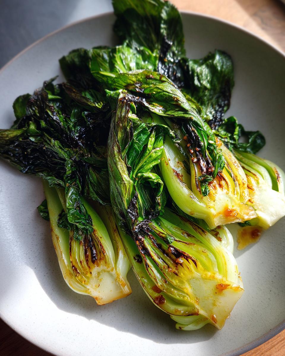 Nahaufnahme von perfekt gebratenem Pak Choi mit schönen Röstaromen auf einem hellen Teller.