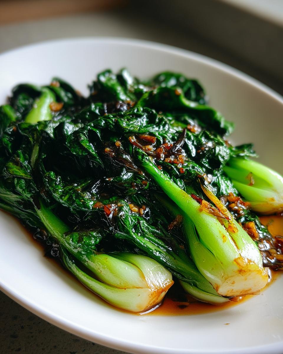 Nahaufnahme von saftigem Gebratener Pak Choi in der Pfanne mit einer dunklen, glänzenden Sauce und Knoblauchstücken.