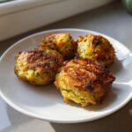 Vier goldbraun gebratene Kohlknödel auf einem weißen Teller, appetitlich angerichtet.