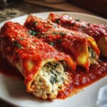 Nahaufnahme von drei Mangold-Cannelloni, gefüllt mit Ricotta und Mangold, bedeckt mit leuchtend roter Tomatensauce.
