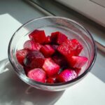 Nahaufnahme von leuchtend roten, gewürfelten Rhabarberstücken in einer Glasschale, bereit für Rhabarberkompott selber machen.