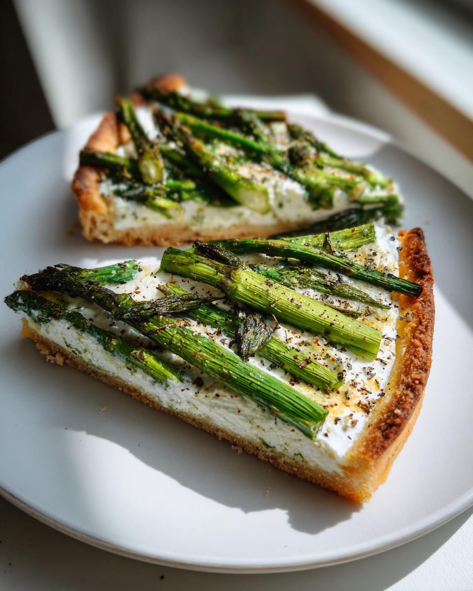 Zwei Stücke Spargel Flammkuchen mit Creme fraiche und grünem Spargel auf einem weißen Teller.