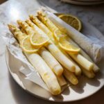 Gedämpfter weißer Spargel mit Zitronenscheiben, bereit zum Servieren nach dem Spargel im Backofen.