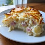 Ein cremiges Stück Spargelauflauf mit Kartoffeln und Schinken mit goldbraun überbackener Käsekruste.